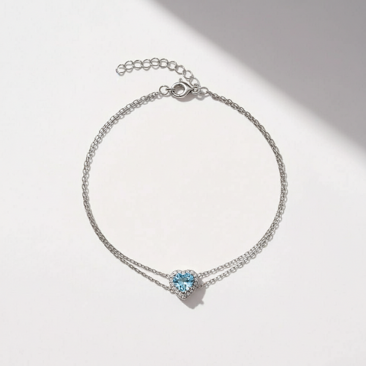 Silver bracelet with a heart-shaped blue gemstone on a light background