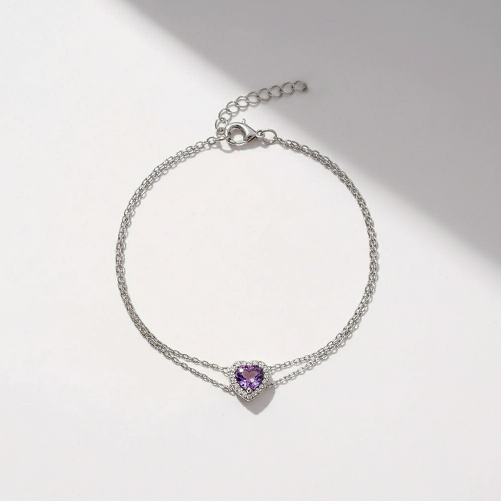 Silver bracelet with a heart-shaped purple gemstone on a light background