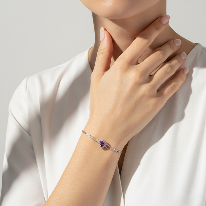 Hand wearing a bracelet with a purple gemstone on a neutral background
