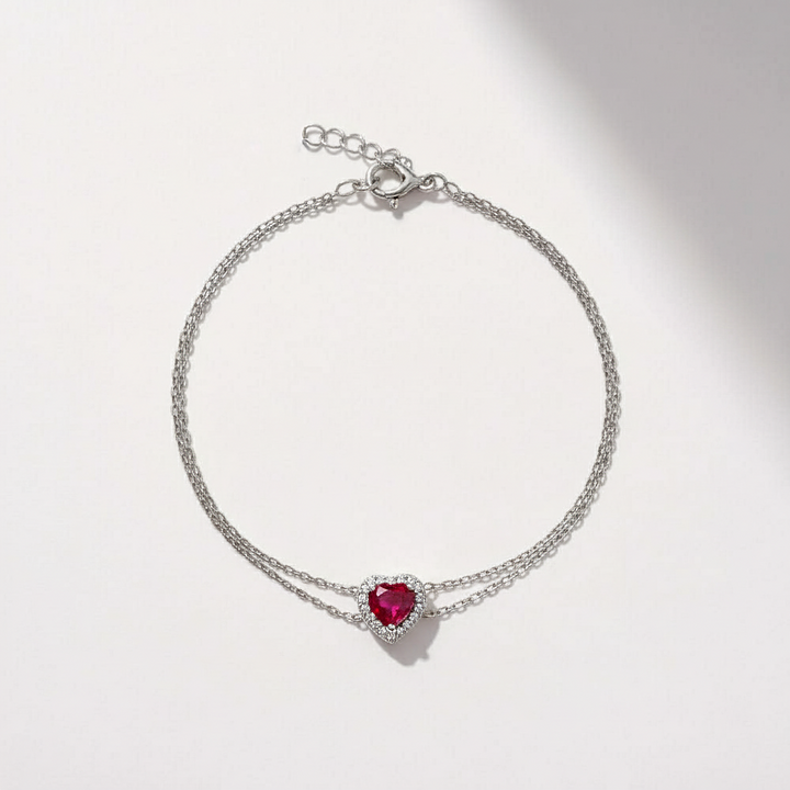 Silver bracelet with a heart-shaped red gemstone on a light gray background