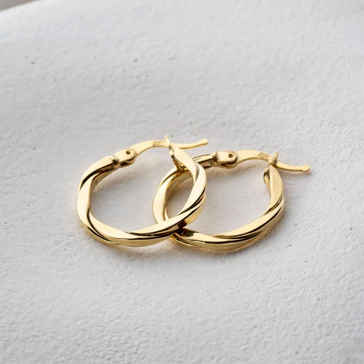 Gold hoop earrings on a light gray background