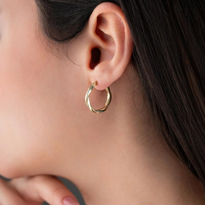 Close-up of a person wearing a gold hoop earring.
