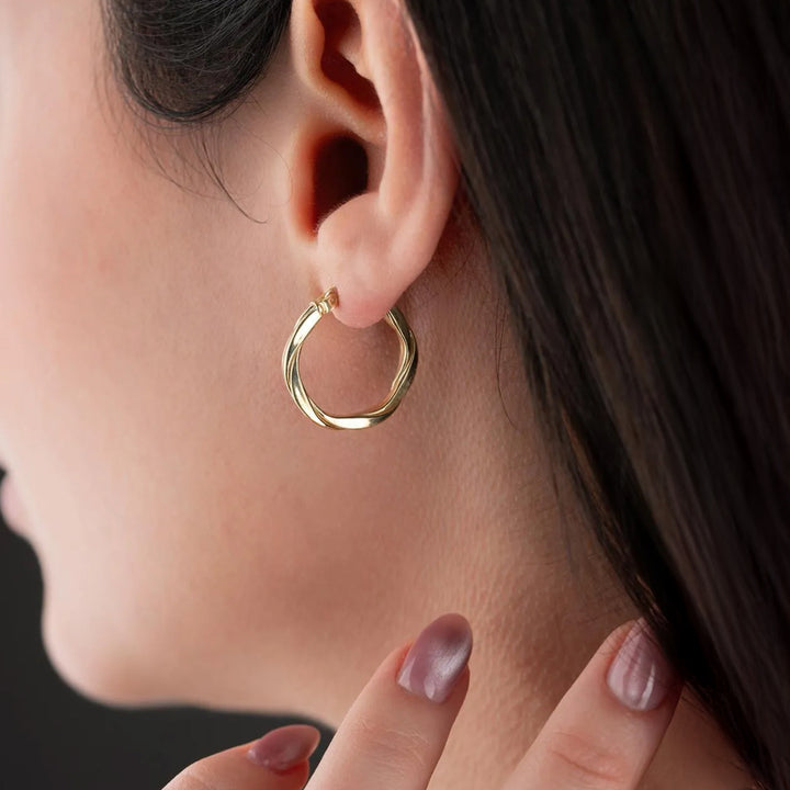 Close-up of a gold hoop earring worn by a person with dark hair.