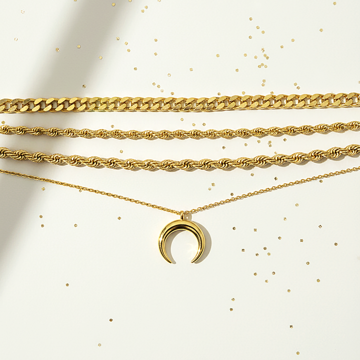 Three gold chain necklaces with a crescent moon pendant on a light background
