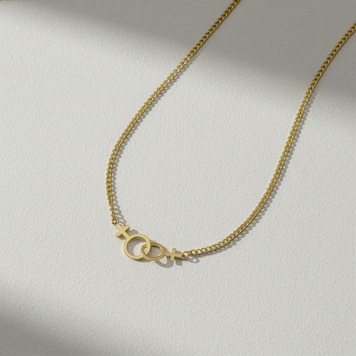 Gold necklace with symbols on a light gray background
