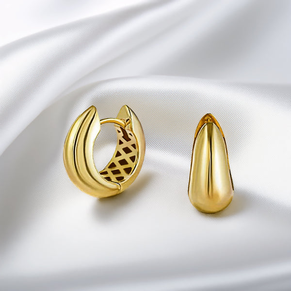 Gold hoop earring and teardrop-shaped earring on a white satin background