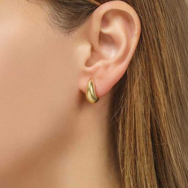 Gold earring worn by a person with brown hair.