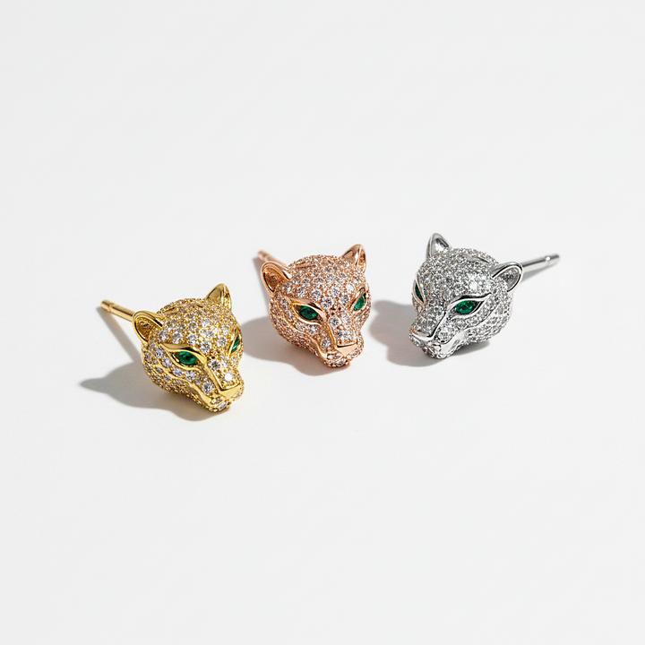 Three cat-themed earrings in gold, rose gold, and silver on a light gray background