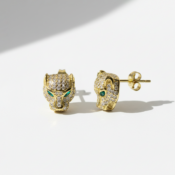 Gold panther head earrings with emerald eyes on a white background