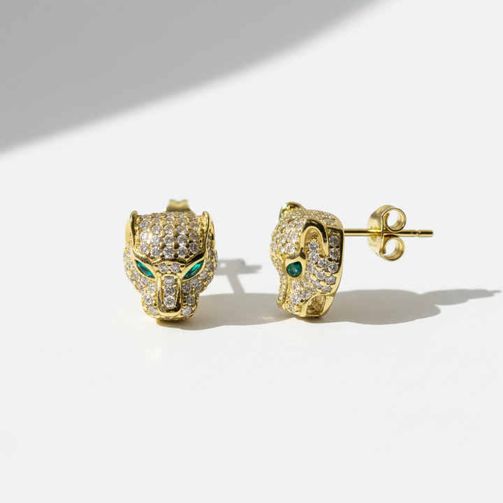 Gold panther head earrings with emerald eyes on a white background