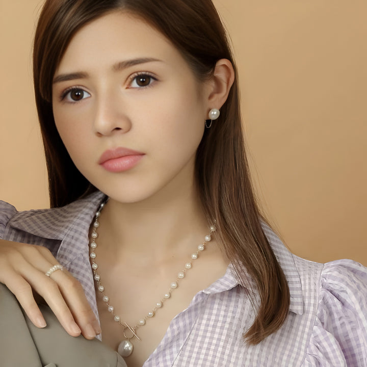 Woman wearing a pearl necklace and earrings against a beige background