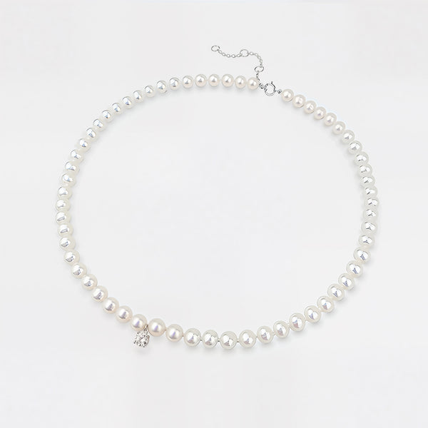 Pearl necklace with a small diamond charm on a light gray background