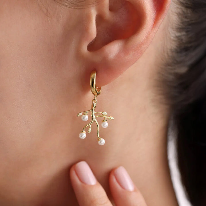 Gold earring with pearl drops worn by a person