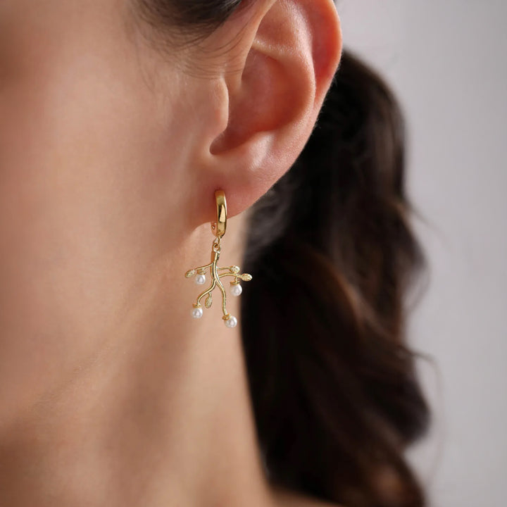 Gold earring with pearl-like beads worn by a person