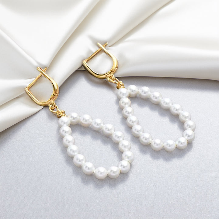 Pearl earrings with gold hooks on a white fabric background