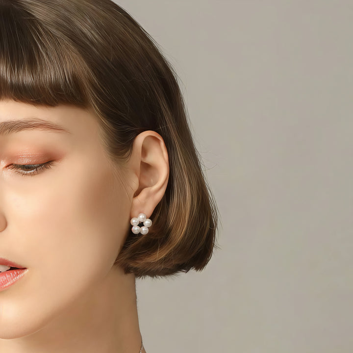 Close-up of a woman wearing pearl earrings with a neutral background