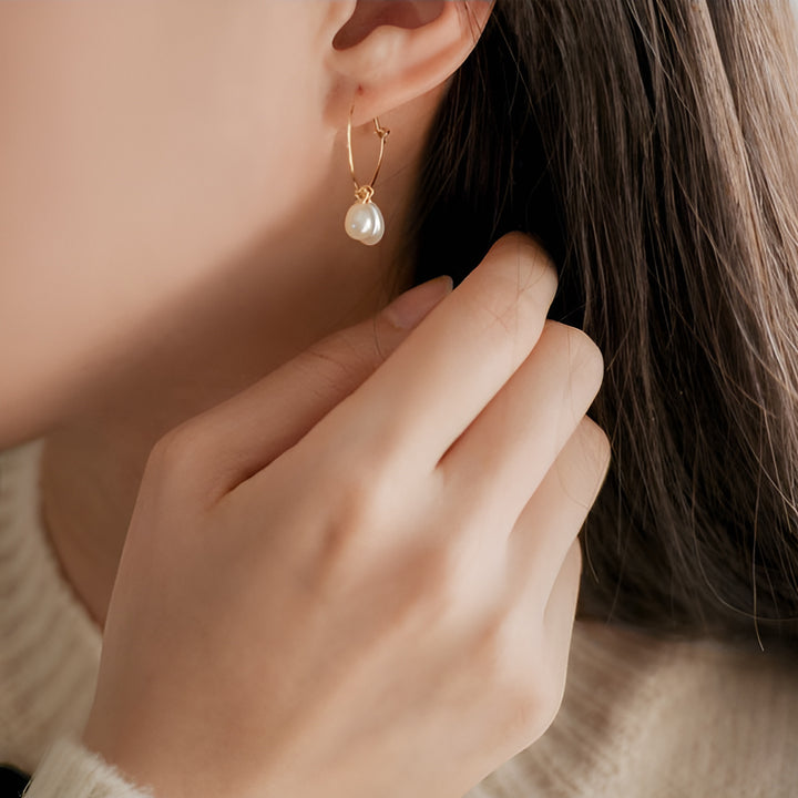 Close-up of a person wearing a pearl earring with a blurred background
