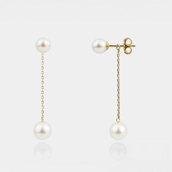 Pearl earrings with gold chains on a white background