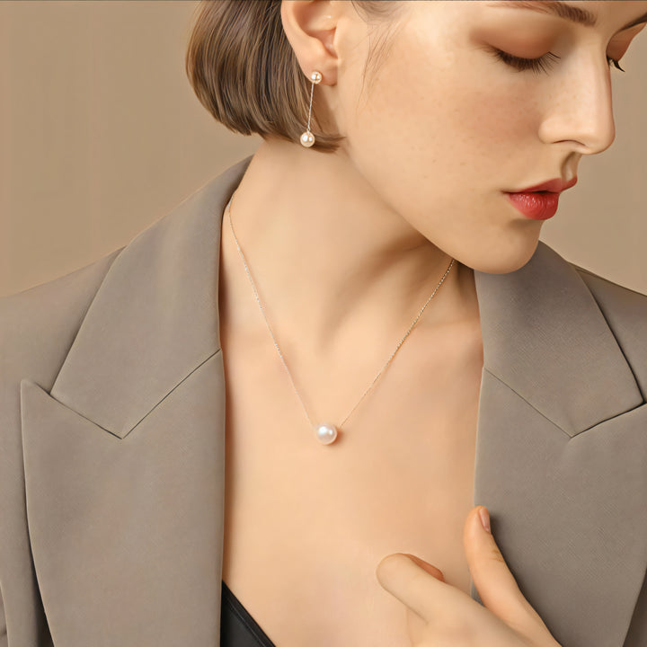 Woman wearing a pearl necklace and earrings against a neutral background