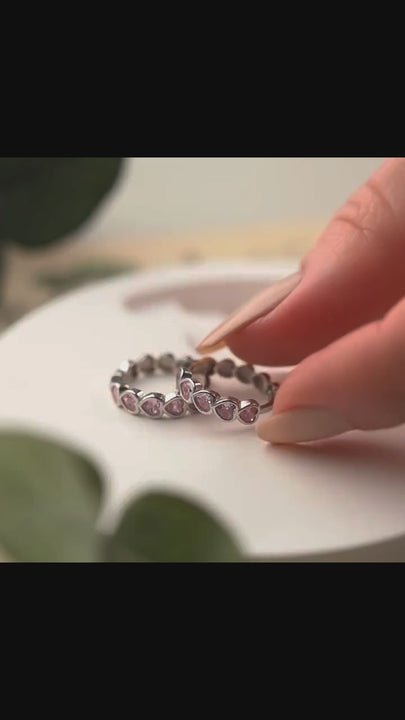 A model wearing heart-shaped hoop earrings with pink gemstones