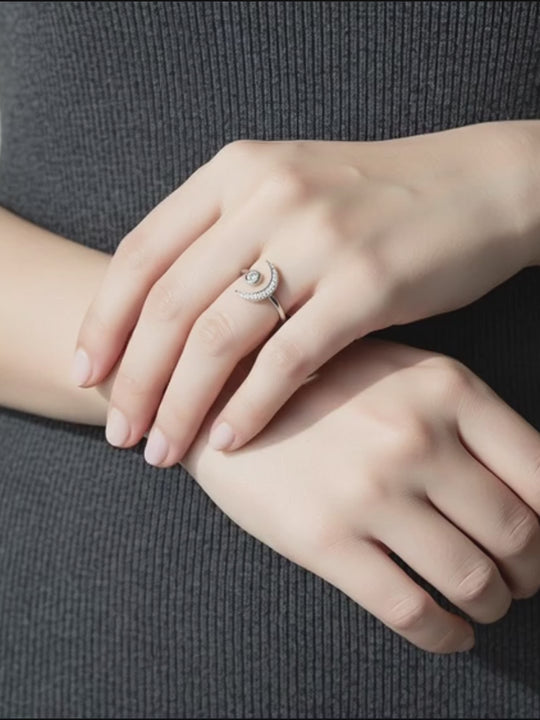 Hand wearing silver moon ring with a gray background