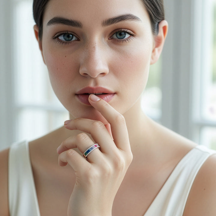 Woman wearing a ring with a colorful gemstone, indoors with a blurred background
