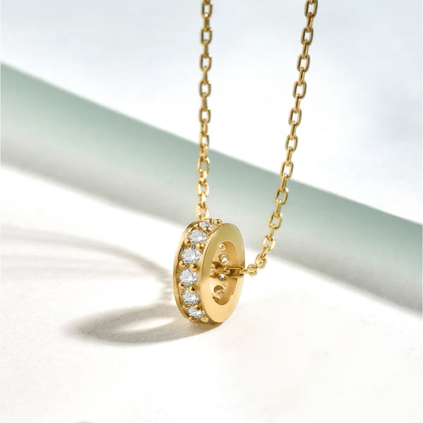 Gold necklace with a round pendant on a light background