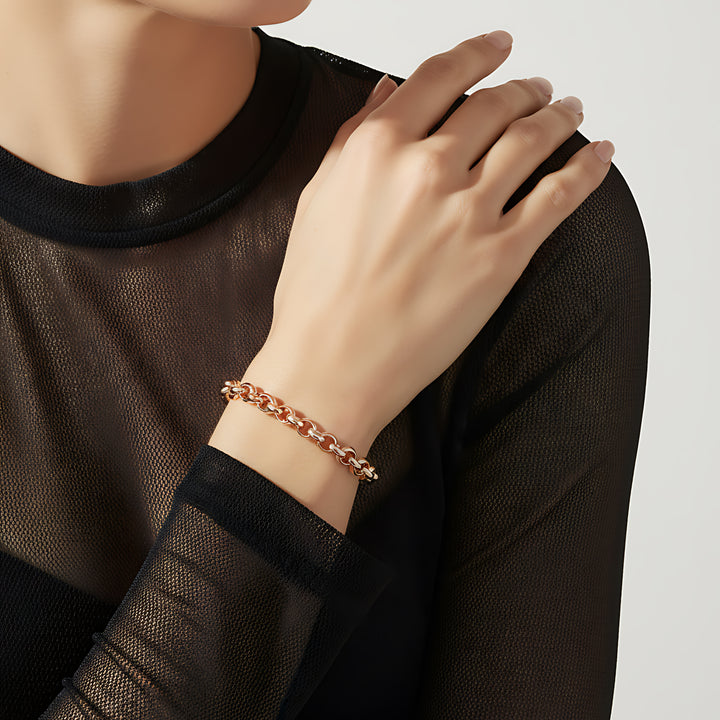 Person wearing a rose gold bracelet on a plain background