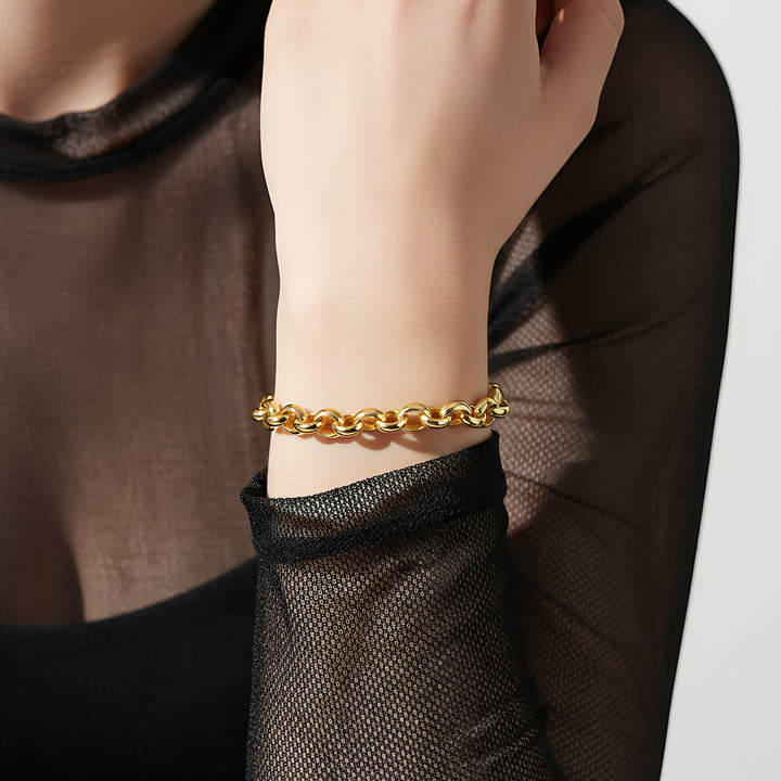 Gold chain bracelet on a wrist with a black sheer sleeve
