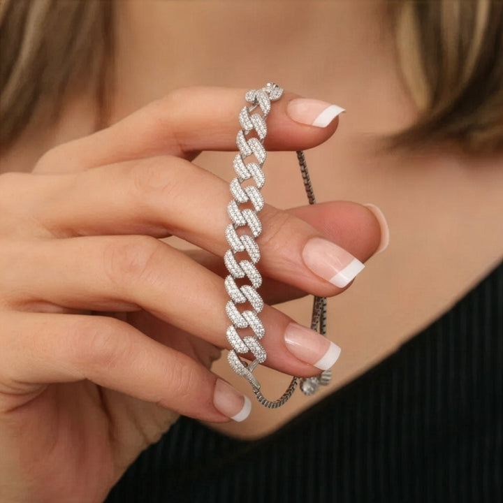 Close-up of a hand holding a diamond studded bracelet against a neutral background