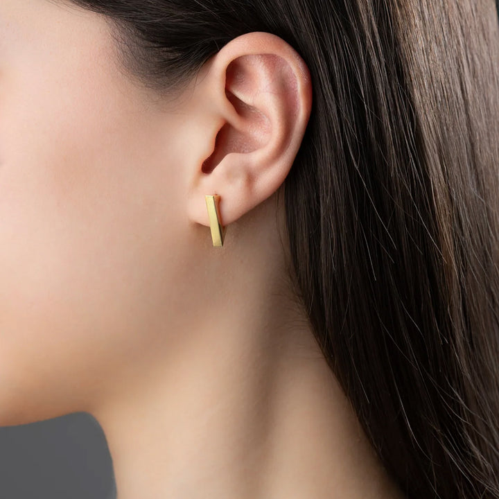 Close-up of a person wearing a gold earring with a blurred background