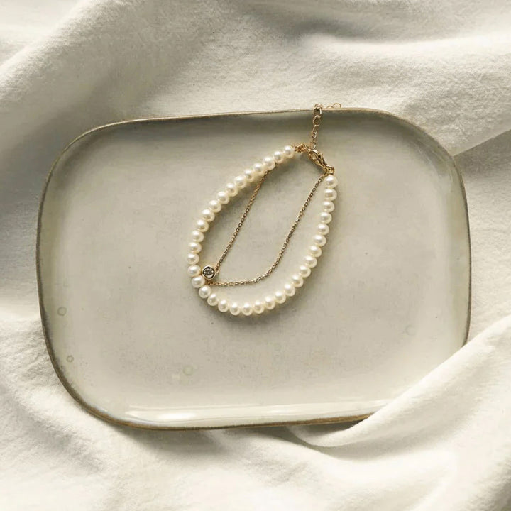 Pearl necklace on a ceramic plate with a soft white background